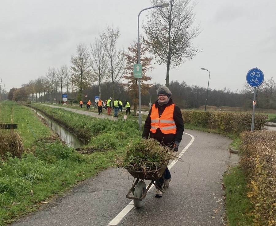 Vrijwilliger met kruiwagen vol maaisel